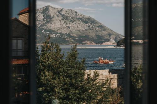 a boat in the water with a mountain in the background at Apartments Trifunovic Old Town in Budva