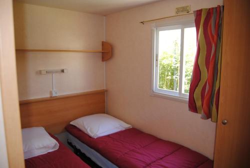 a small room with two beds and a window at LES PIERRES CHAUDES in Veyrignac