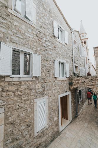 a stone building with white shutters on a street at Apartments Trifunovic Old Town in Budva