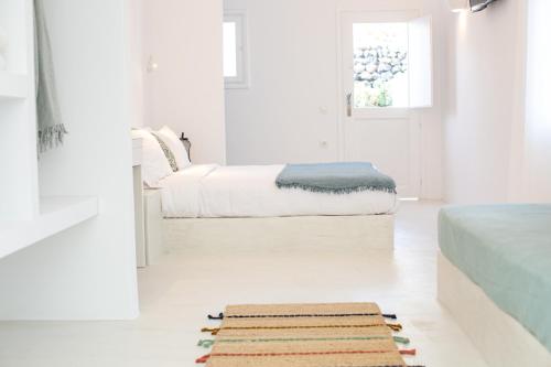 a white room with a bed and a rug on the floor at Apanomeria Boutique Residence in Oia