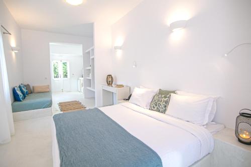 a white bedroom with a large bed with a blue blanket at Apanomeria Boutique Residence in Oia
