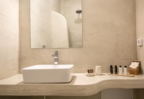 a bathroom with a white sink and a mirror at Apanomeria Boutique Residence in Oia