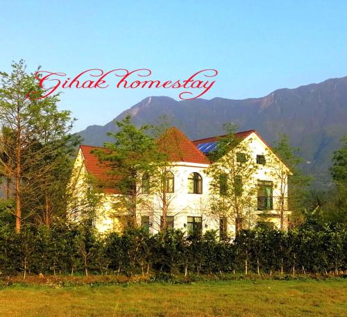 a white house with a mountain in the background at Gihak Homestay in Pinghe