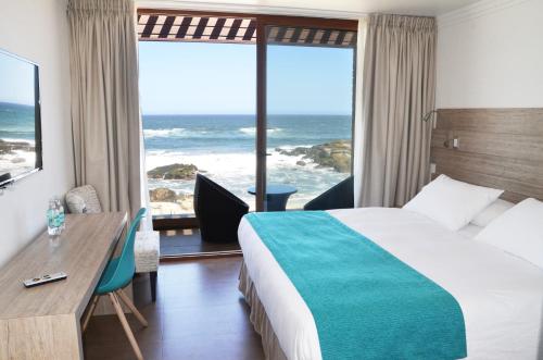 a hotel room with a bed and a view of the ocean at Hotel Mae in Maitencillo