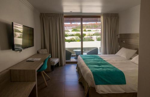 a hotel room with a bed and a desk and a window at Hotel Mae in Maitencillo