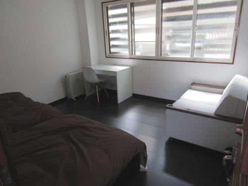 1 dormitorio con cama, escritorio y ventana en Yuzawa Condo 一棟貸 貴重な駐車場2台無料 en Yuzawa