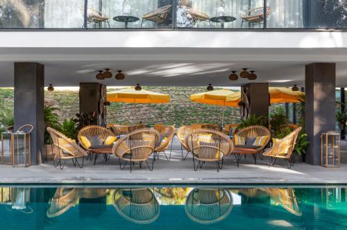 a table with chairs and umbrellas next to a pool at LAVIDA Hotel at Camiral, a Quinta do Lago Resort in Caldes de Malavella