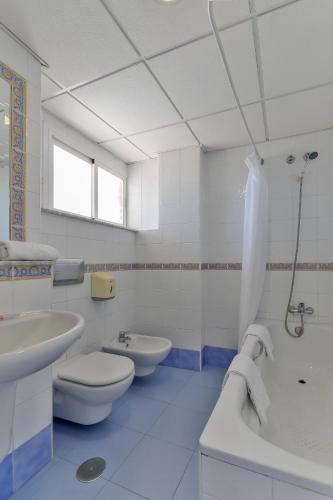 a bathroom with two sinks and a toilet and a shower at Hotel Polamar in Santa Pola