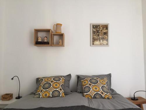 um quarto com uma cama com duas almofadas e uma parede branca em Au Coin des Cerisiers em Montclus