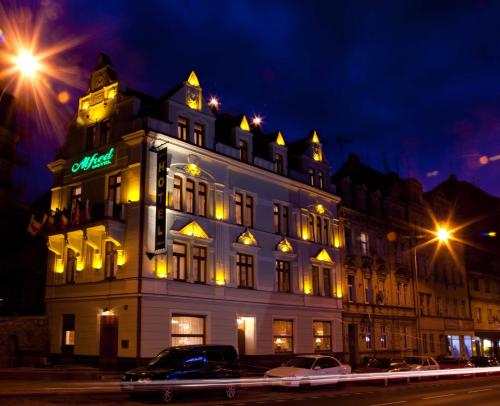 a large white building with a neon sign on it at Hotel Alfred in Karlovy Vary