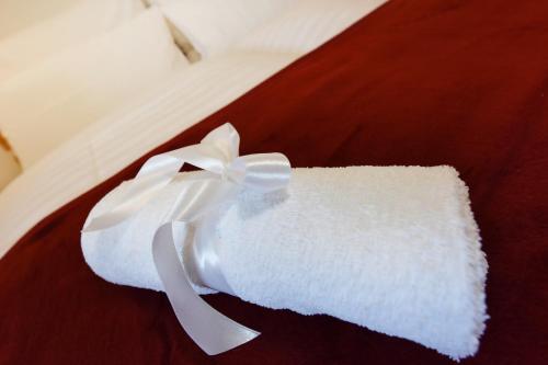 a white towel with a white ribbon on a bed at Hof Lässer in Möggers