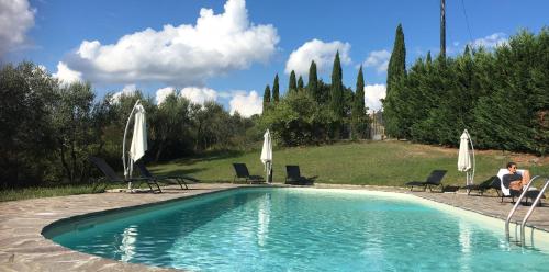 a swimming pool with chairs and white umbrellas at Farmhouse B&B Il Paretaio in Barberino di Val dʼElsa