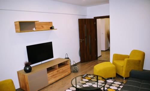 uma sala de estar com uma televisão de ecrã plano e cadeiras amarelas em Center City Apartment II em Nitra