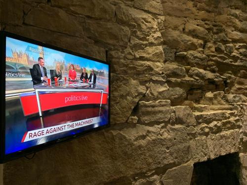 a tv on a stone wall with a tv on it at Royal Mile Suites by the Castle in Edinburgh