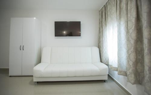 a white chair sitting in a room with a tv at Pansion Kipovi in Tuzla