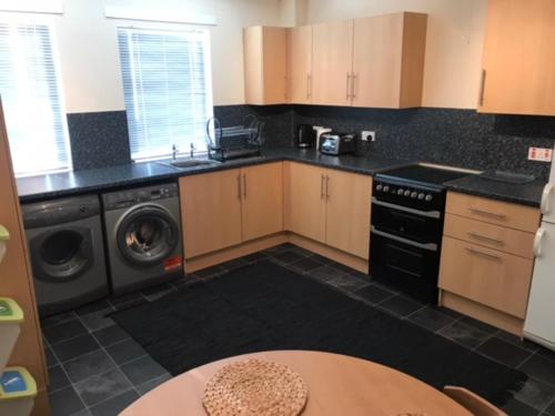 a kitchen with a stove and a sink and a table at Thurso Self Catering Pet Friendly Holiday Lets in Thurso