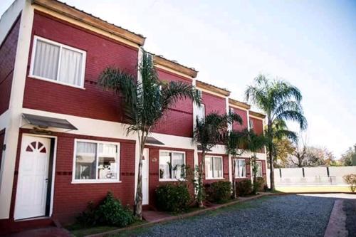 a red house with palm trees in front of it at Cabañas Boulevard in Chascomús