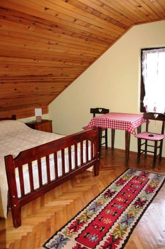Un dormitorio con una cama, una mesa y una alfombra. en Putnicka kuca kod Dragane, en Bajina Bašta