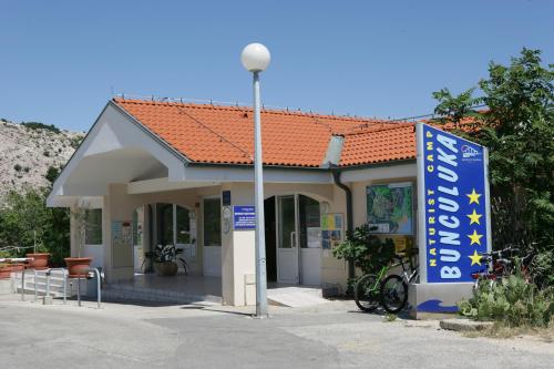 a small building with a sign in front of it at FKK Bunculuka Camping Resort by Valamar in Baška