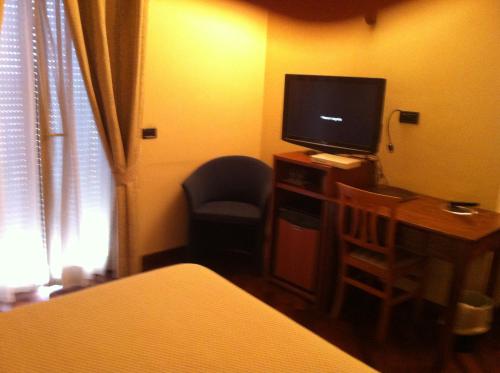 a bedroom with a bed and a tv and a chair at Hotel il Cigno in Perugia