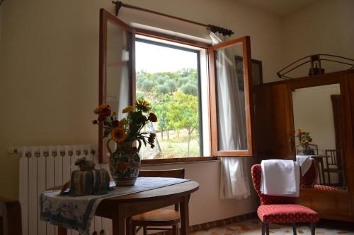 eine Vase mit Blumen auf einem Tisch vor einem Fenster in der Unterkunft Affittacamere La Fornace in Rigomagno