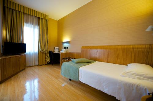 a bedroom with a bed and a desk and a television at Best Western Hotel Luxor in Turin