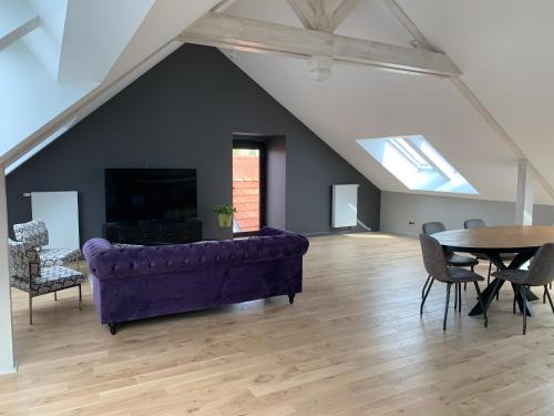 a living room with a purple couch and a table at L'appartement et les Suites de VJL... in Avize