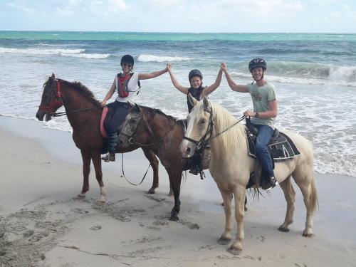 three people are riding horses on the beach at carré coco in Sainte-Luce