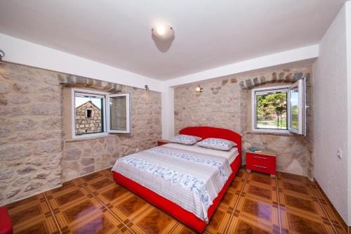 a bedroom with a red bed and two windows at VILLA FENIX PODGORA in Podgora