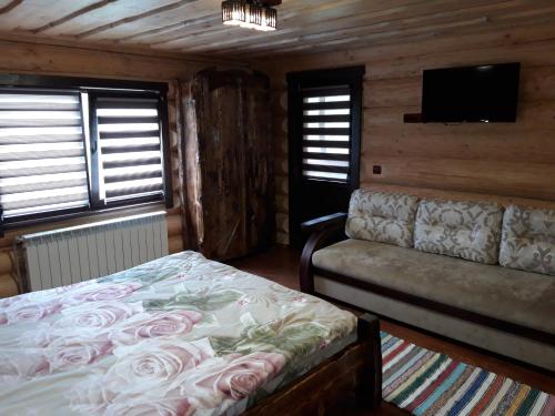 a bedroom with a bed and a couch and a flat screen tv at Маєток горгани in Synevyrsʼka Polyana