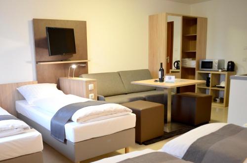 a hotel room with two beds and a couch at Hana Aparthotel in Hamburg