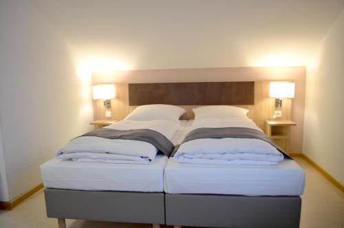 two beds in a room with two lamps at Hana Aparthotel in Hamburg