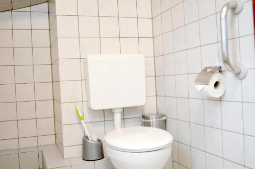 a bathroom with a toilet in a white tiled wall at Hana Aparthotel in Hamburg