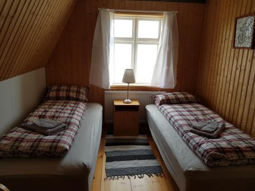 2 Betten in einem kleinen Zimmer mit Fenster in der Unterkunft Brjánslækur Gamli bærinn in Brjánslækur