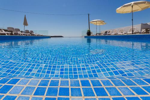 uma piscina azul com cadeiras e guarda-sóis em Mareta Beach - Boutique Bed & Breakfast em Sagres