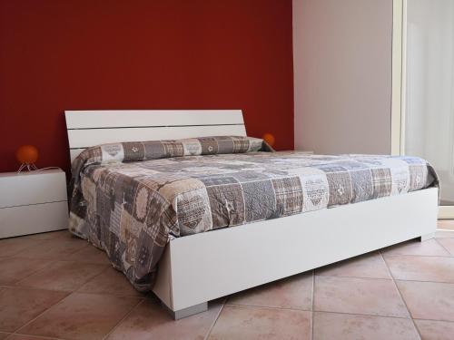 a white bed in a bedroom with a red wall at Holiday Beach Lumia in Sciacca