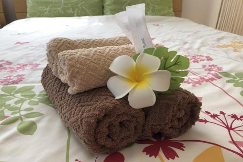 a pile of towels and a flower on a bed at TerraceRin YN12 in Tomigusuku