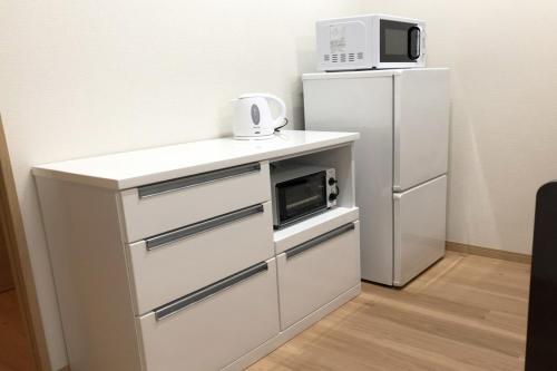 a small kitchen with a microwave and a refrigerator at TerraceRin YN12 in Tomigusuku