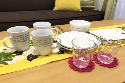 a table with three cups and plates and glasses at TerraceRin YN12 in Tomigusuku