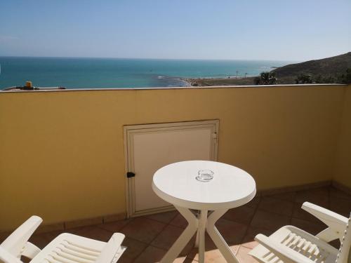a white table and chairs on a balcony with the ocean at Holiday Beach Lumia in Sciacca