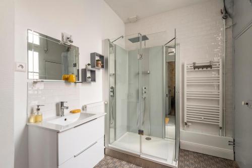ein weißes Badezimmer mit Dusche und Waschbecken in der Unterkunft Le cœur de Reims, la mairie et le Boulingrin in Reims