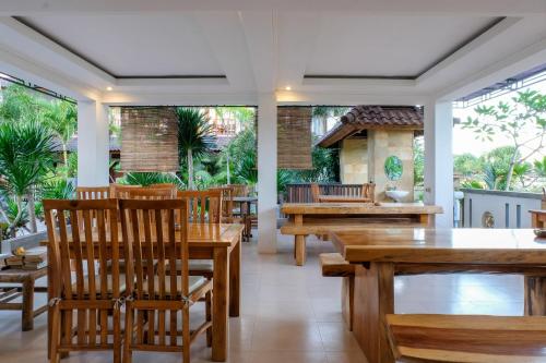 a dining room with wooden tables and chairs at Friends Beach Hotel in Kuta Lombok