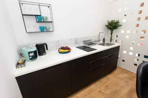 a kitchen with black cabinets and a sink at Bliss Apartments in Poznań