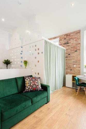 a green couch in a living room with a brick wall at Bliss Apartments in Poznań
