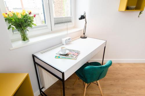 a white desk with a lamp and a green chair at Bliss Apartments in Poznań