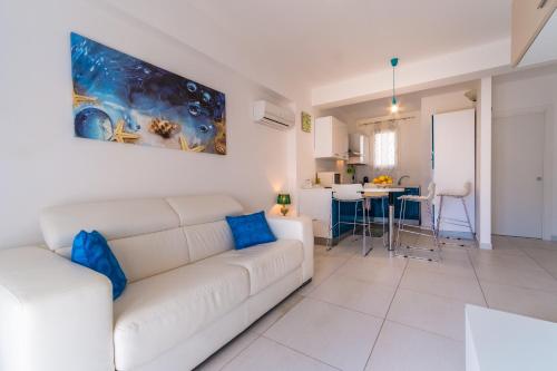 Sala de estar blanca con sofá blanco y almohadas azules en Apartment window on the sea, en Santo Stefano di Camastra