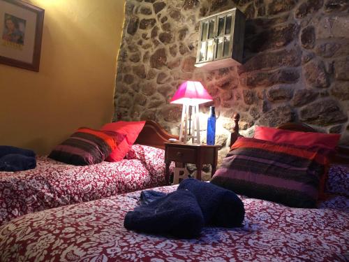 two beds in a room with a stone wall at El Balcon de Los Sueños in Trevejo