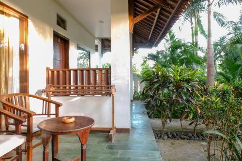 a porch with a table and chairs and plants at Friends Beach Hotel in Kuta Lombok