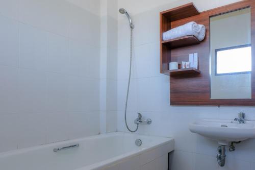 a bathroom with a bath tub and a sink at Friends Beach Hotel in Kuta Lombok