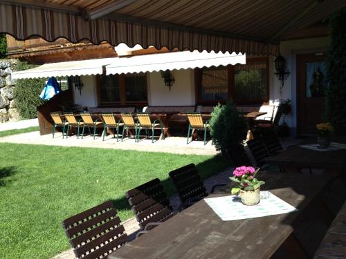a patio with chairs and a table with a white umbrella at Berggasthof Hintergföll in Unken